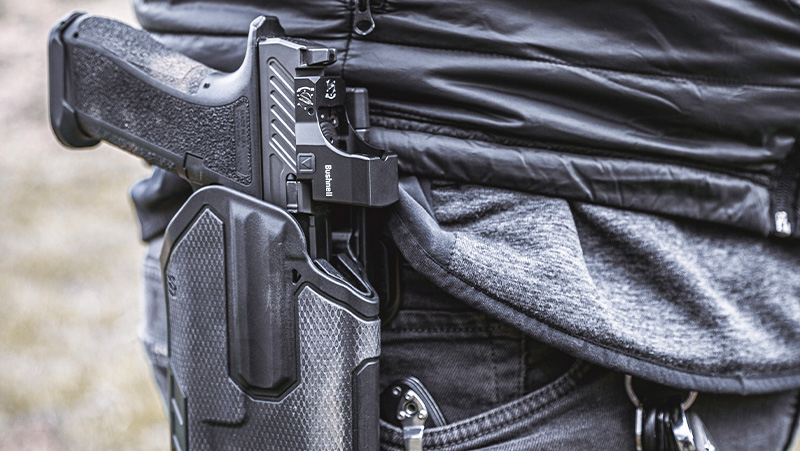A person discreetly concealing a gun in their pocket, using a pocket holster for added security